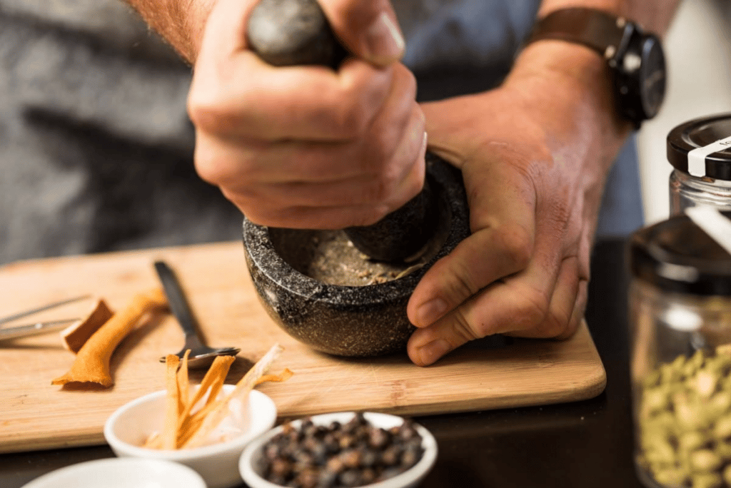 A man pounding spices in a mortar and pestle at McHenry Distillery