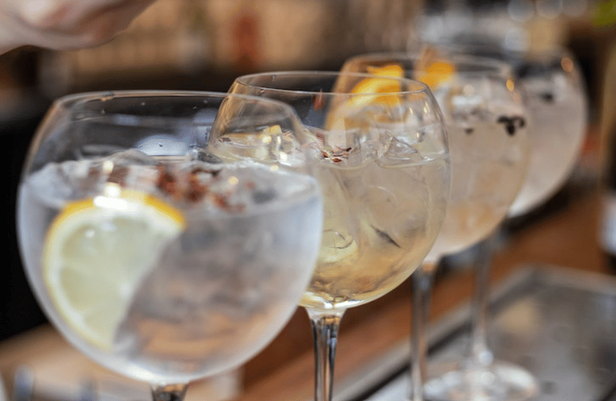 4 cocktails in stemmed glass along a bar